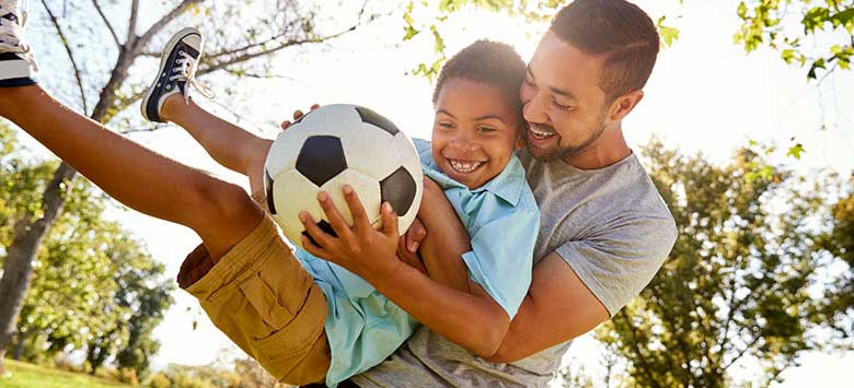 Father and son playing soccer.