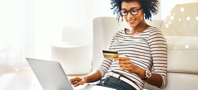 Woman in living room using a credit card to make a purchase online.
